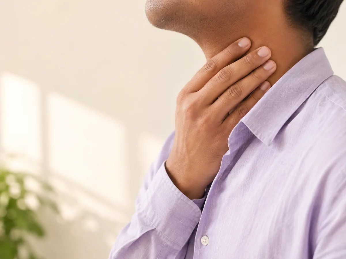 A single hand raised to one side of the neck